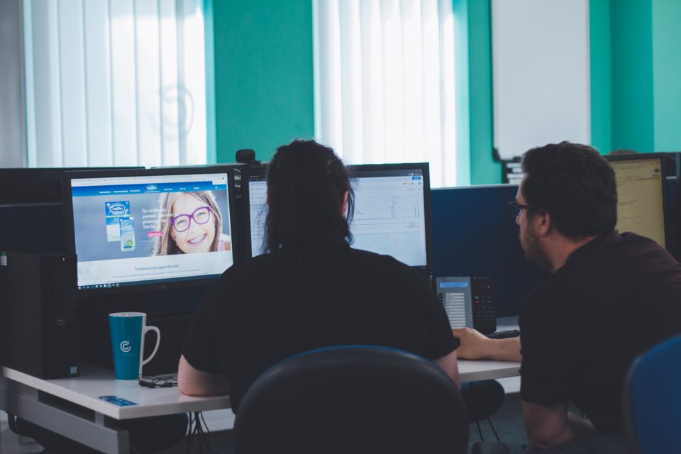 some of the SEO team working at a desk and discussing what is on the screen